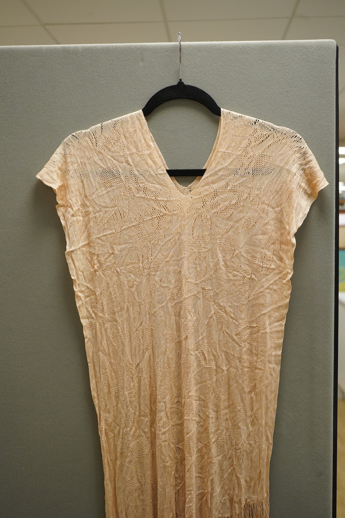 A 1920’s-30’s silk stockinette fringed ladies open sided knitted tabard, sides 56cm long not including fringe. Condition - front point of V slightly worn.